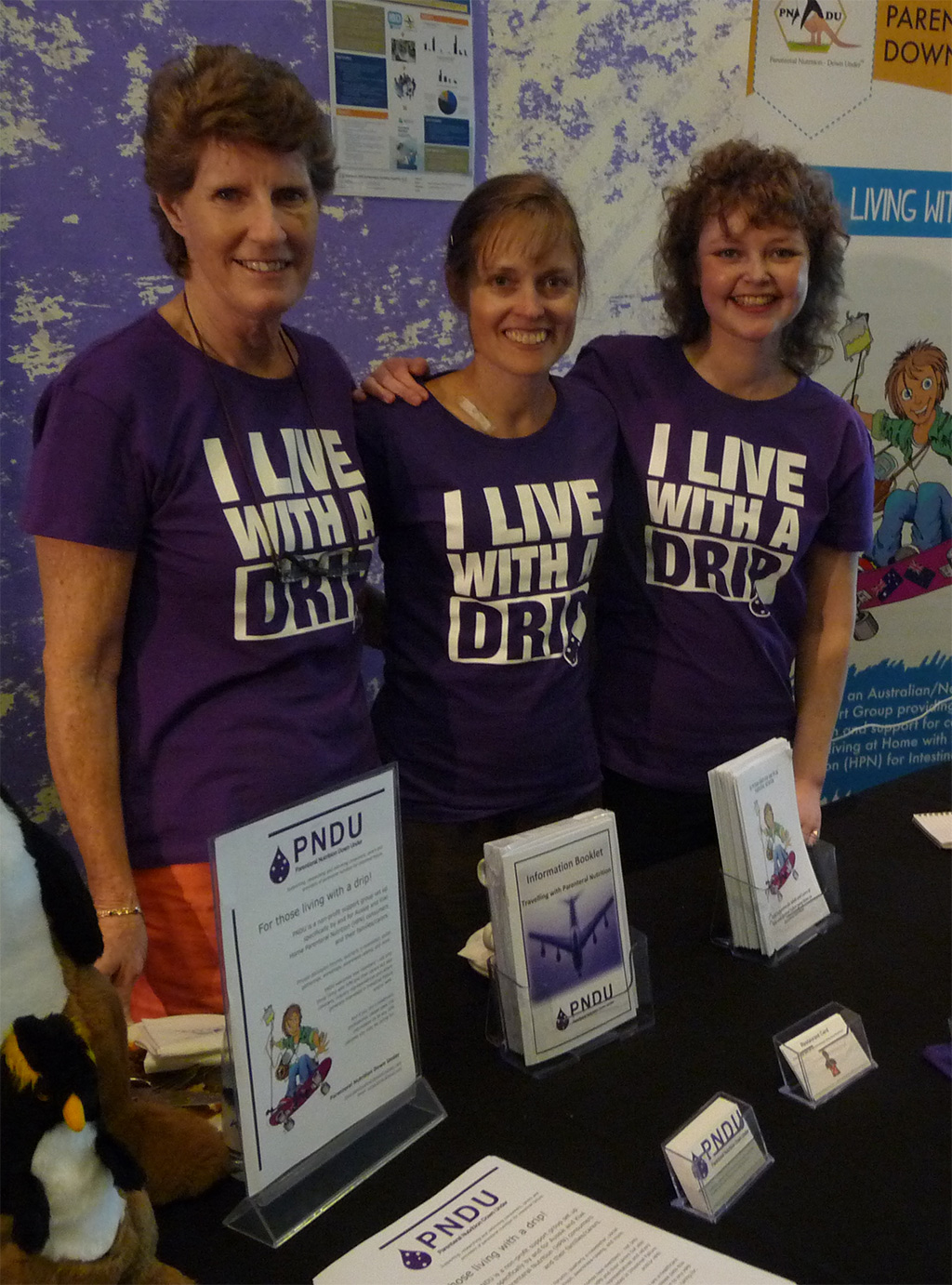 Women at PNDU stand wearing I Live With A Drip tshirts